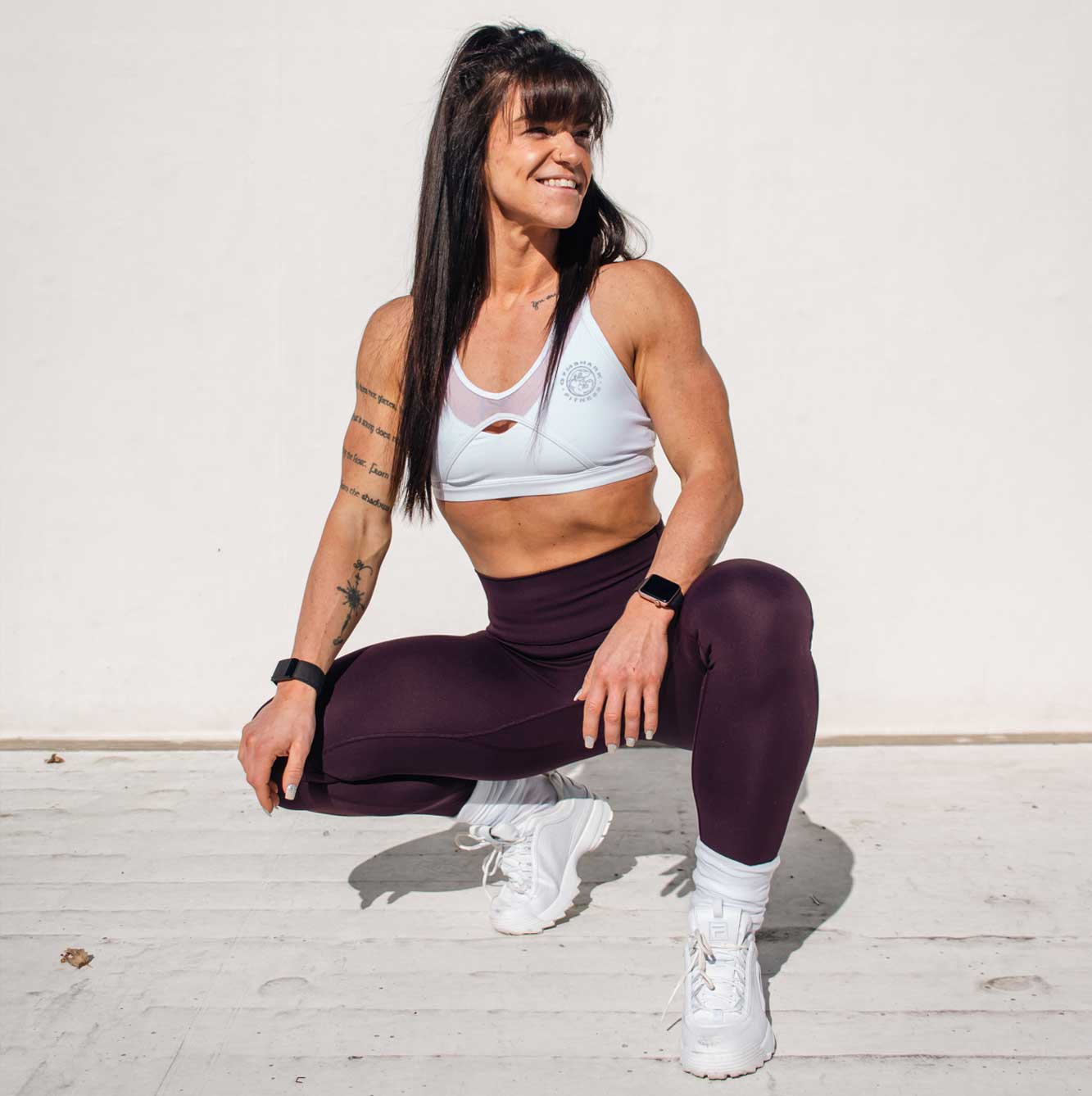 Fitness coach seated outdoors, basking in the sunlight, dressed in athletic attire.